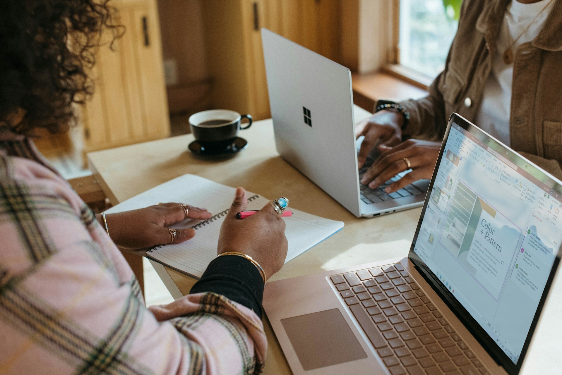 Two people sat opposite each other on a table collaborating on laptops